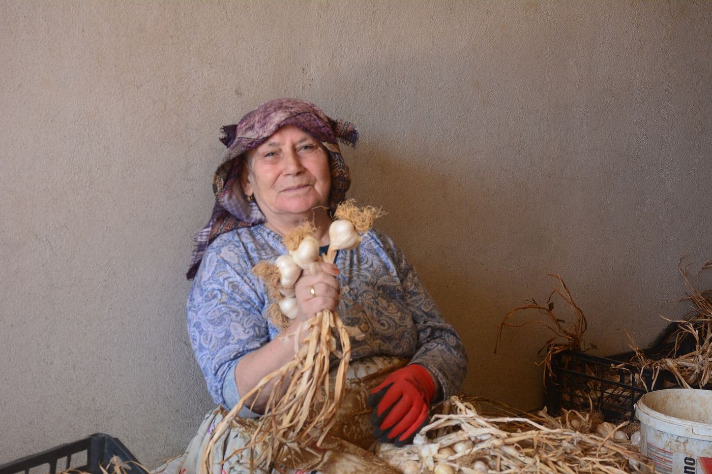 Elinde sarımsak demetleri tutan kadın çiftçi